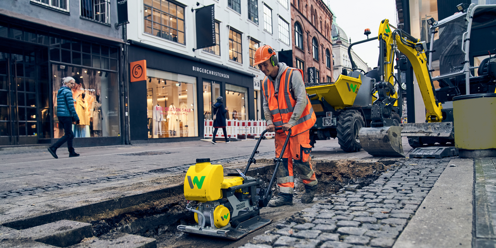 een man die op een bouwplaats in de binnenstad werkt met een lichte trilplaat