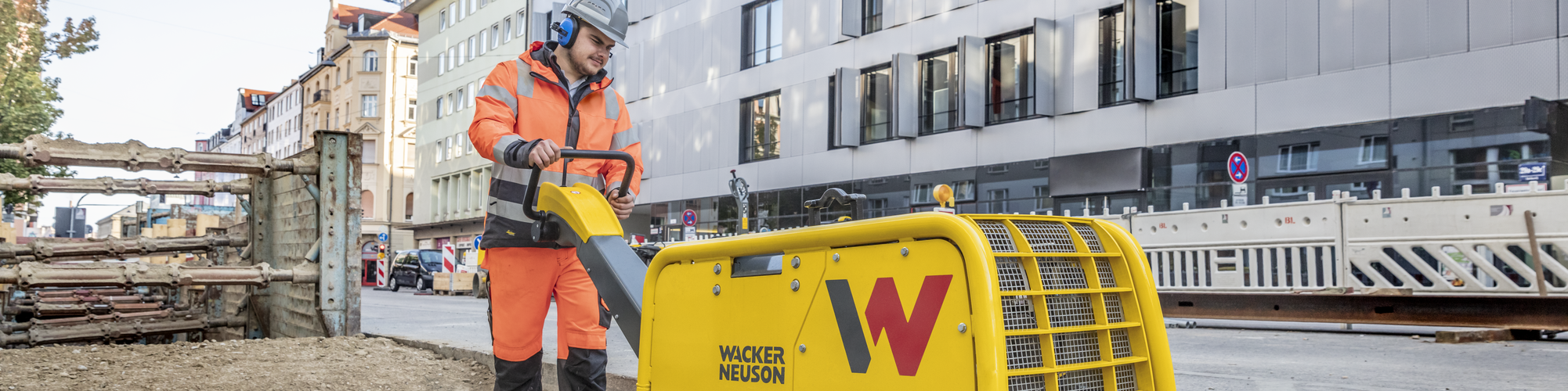 Een Wacker Neuson-trilplaat in actie op een bouwplaats in de stad.