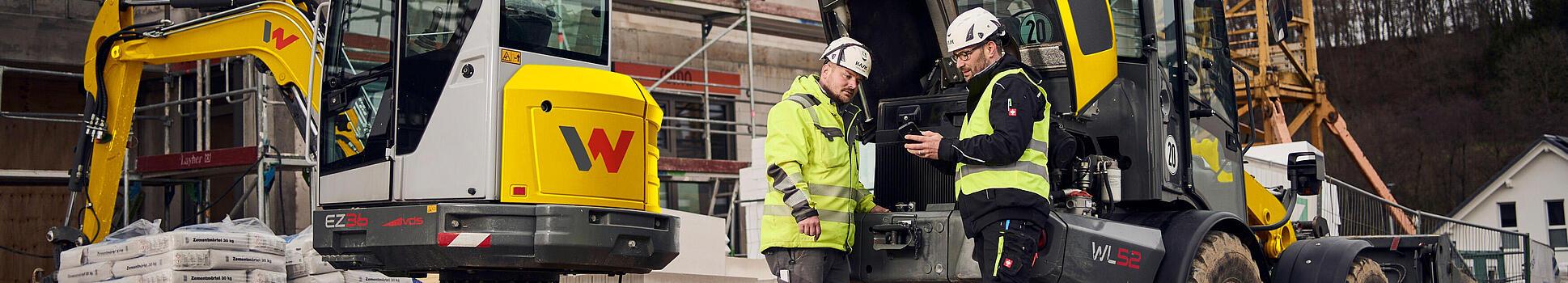 two customers standing in front of wacker neuson machines