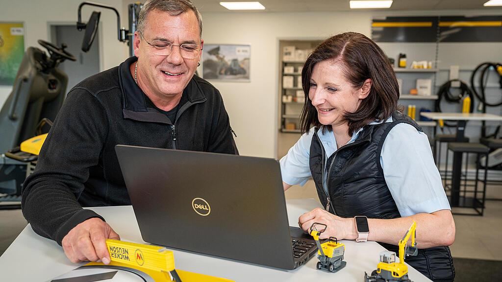 two persons discussing in front of a laptop