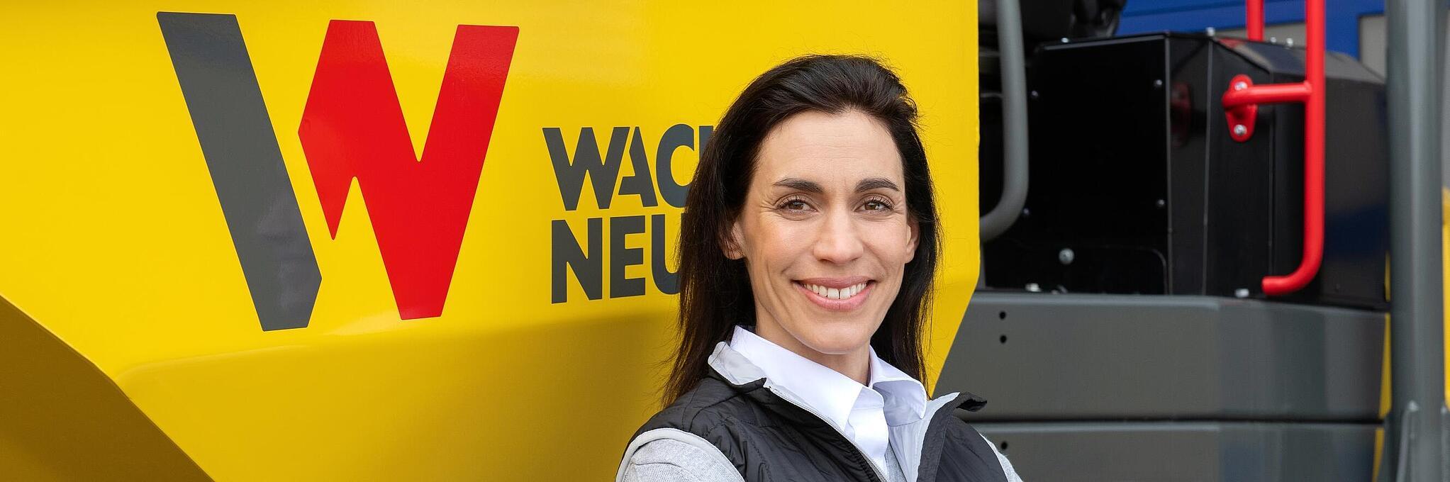 Wacker Neuson employee standing and smiling with arms folded in front of a Wacker Neuson wheel dumper.